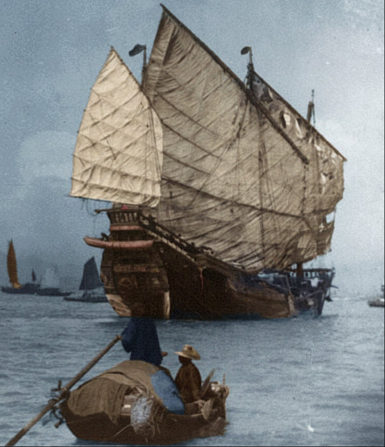 Vintage black and white photograph of a large sailing ship on water with smaller boats in the background.